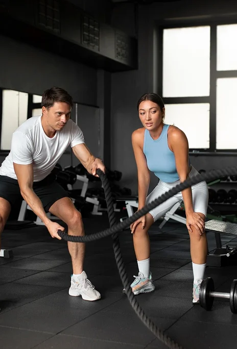 Fitness Man and woman working out with battle ropes